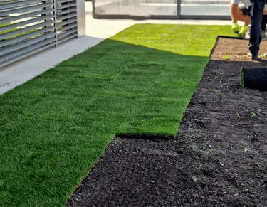 Fresh sod being laid on a modern patio area